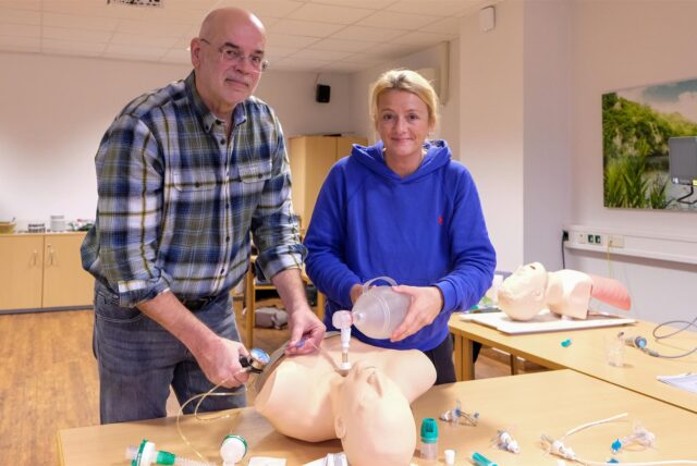 Dr. Martin Montag und Isabel Seiler-Gebauer führen an einer Puppe eine Reanimation mit Luftröhrenschnitt durch.