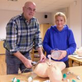 Dr. Martin Montag und Isabel Seiler-Gebauer führen an einer Puppe eine Reanimation mit Luftröhrenschnitt durch.