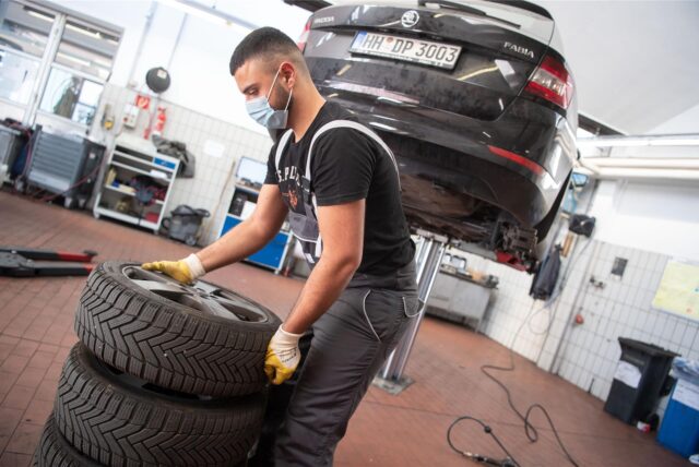 Ein Automechaniker stapelt in der Werkstatt Autoreifen.