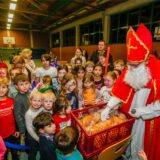 Ein Mann im Nikolaus-Kostüm steht in einer Dortmunder Turnhalle und verteilt Backteilchen an die um ihn herum stehenden Kinder.