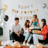 Ein Mann und drei Frauen sitzen auf der Couch und gratulieren zum 30. Geburtstag.