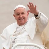 Papst Franziskus lächelt und winkt.