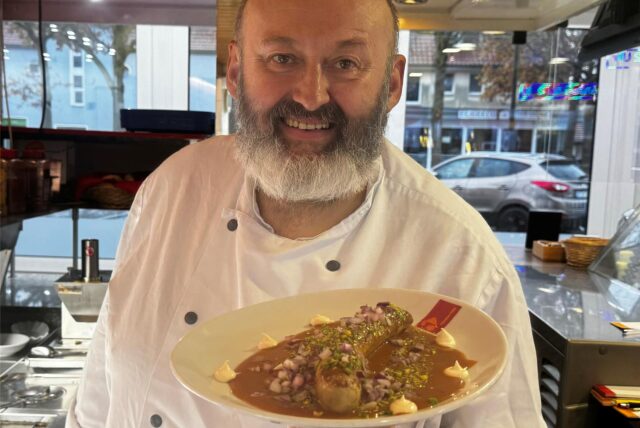 Imbissbesitzer Peter Finke von Hähnchen Finke in Dorsten hält einen Teller mit seiner Dubai-Currywurst in der Hand.