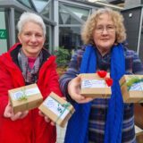 Zwei Frauen halten kleine Päckchen in der Hand.