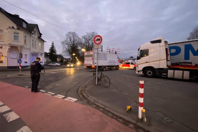 Ein Polizist steht an einer Kreuzung und nimmt einen Unfall auf.