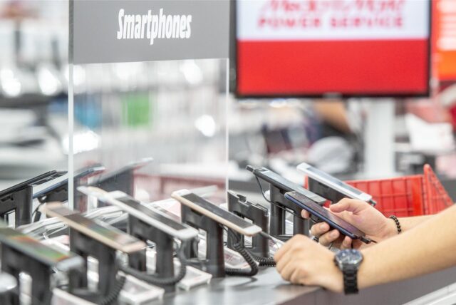 Kunden schauen sich in einer Media Markt Filiale die neuesten Smartphones in der Auslage an
