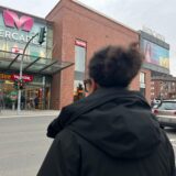 Eine Frau mit einer dunklen Jacke steht an einer Ampel gegenüber den Mercaden in Dorsten.