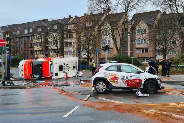 Ein Rettungswagen liegt in Mülheim an der Ruhr auf der Seite, ein kleines Lieferantenauto steht daneben. Betriebsstoffe sind ausgelaufen.