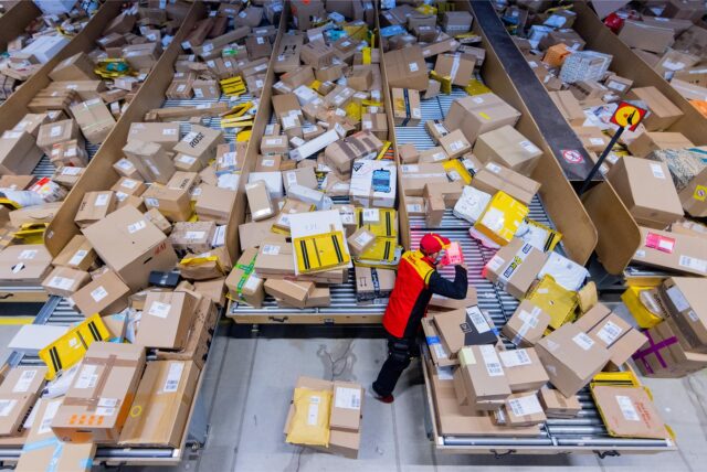Ein DHL-Mitarbeiter sortiert zu Weihnachten viele Pakete.