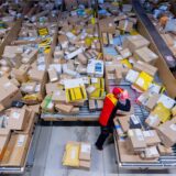 Ein DHL-Mitarbeiter sortiert zu Weihnachten viele Pakete.