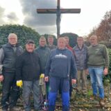 Acht Helfer stehen nach vollendeter Tat vor dem neuen Holzkreuz auf dem Friedhof in Recklinghausen-Speckhorn