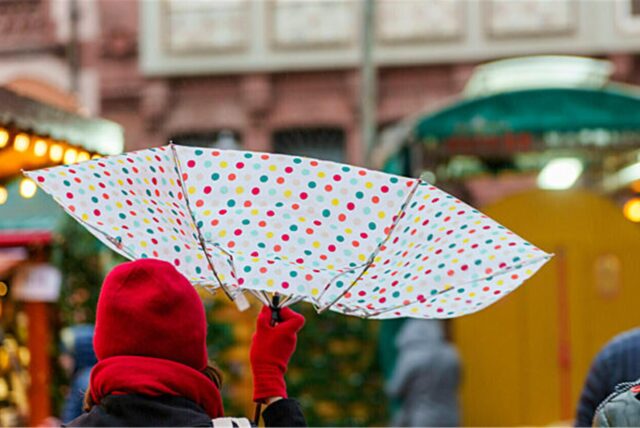 Eine Frau geht mit einem Regenschirm über den Weihnachtsmarkt.