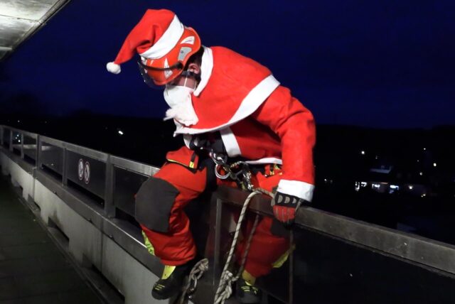 Ein als Nikolaus verkleideter Höhenretter der Feuerwehr steigt an der Kinderklinik in Datteln über ein Geländer, um sich abzuseilen.