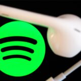 Symbolbild: Das grüne Logo des Streaming-Dienstes Spotify, daneben ein weißer Kopfhörer.