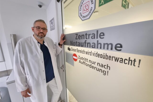 Ein Arzt steht vor der Tür der zentralen Notaufnahme eines Krankenhauses.