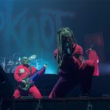 Der Sänger von Slipknot steht am Bühnenrand und singt, im Hintergrund stehen einer der Gitarristen und das Schlagzeug.