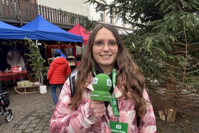 Lara Teschers steht mit einem Mikrofon auf einem Marktplatz.