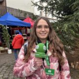 Lara Teschers steht mit einem Mikrofon auf einem Marktplatz.