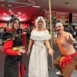 Zwei Frauen und ein Mann haben sich verkleidet. Der Mann sieht aus wie der kleine Avatar, mit blauem Pfeil auf dem Kopf. Die Frauen tragen ebenfalls Kostüme.