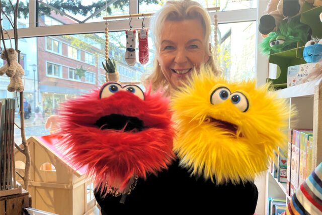 Susanne Wenzel hält eine kuschelige rote und gelbe Handpuppe in ihren Händen.