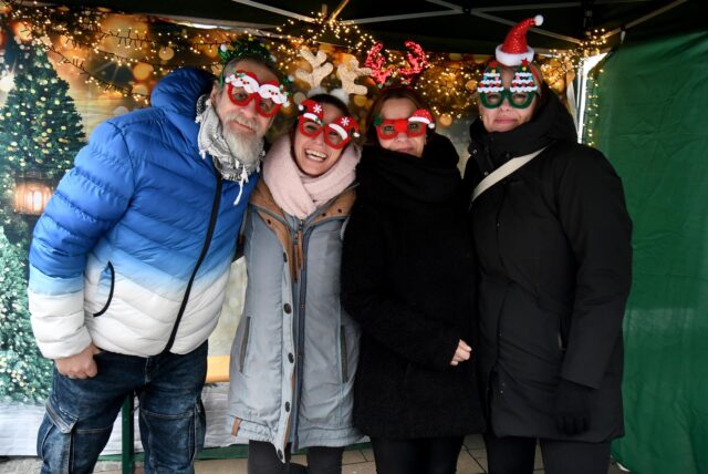 Drei Frauen und ein Mann stehen weihnachtlich kostümiert nebeneinander und lächeln freundlich in die Kamera.