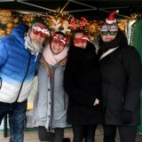 Drei Frauen und ein Mann stehen weihnachtlich kostümiert nebeneinander und lächeln freundlich in die Kamera.