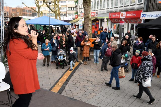 Sängerin Malin Lewis steht beim Wintertreff in der Hertener Innenstadt auf der Bühne, vor der viele Männer und Frauen stehen und zuhören.