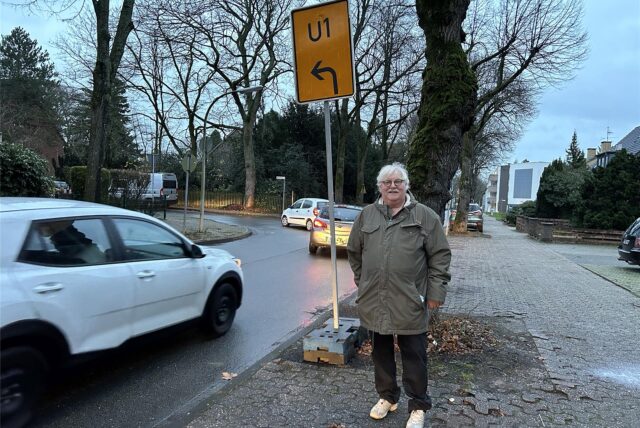 Dr. Michael Bauer steht an einem Umleitungsschild, hinter ihm Autos.