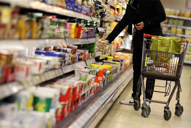 Ein Kunde nimmt in einem Supermarkt etwas aus dem Kühlregal.
