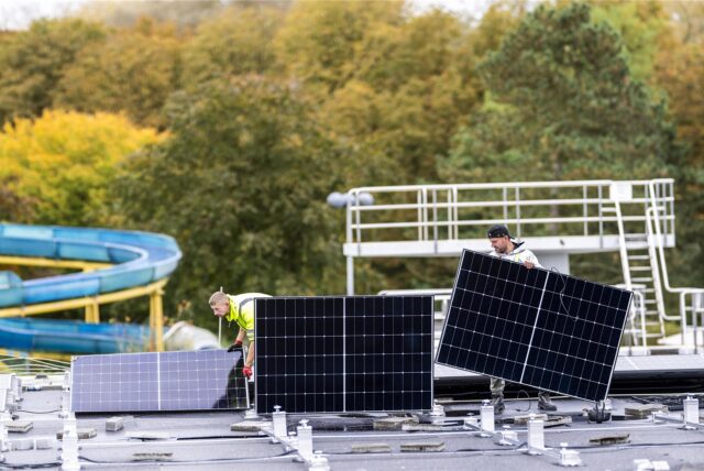 Arbeiter bauen am Freizeitbad Aquarell in Haltern eine Photovoltaik-Anlage auf das Dach eines Carports.
