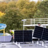 Arbeiter bauen am Freizeitbad Aquarell in Haltern eine Photovoltaik-Anlage auf das Dach eines Carports.