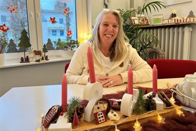 Susanne Warnke sitz am Tisch, vor ihr ein Adventsgesteck.