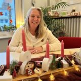 Susanne Warnke sitz am Tisch, vor ihr ein Adventsgesteck.