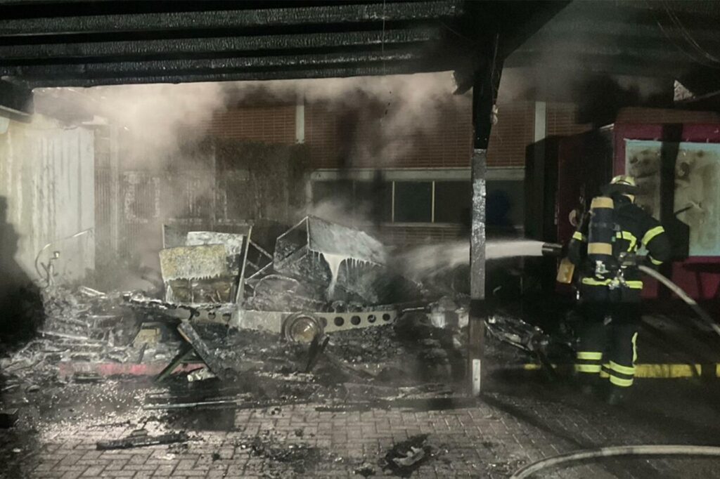 Feuerwehrleute löschen einen qualmenden Trümmerhaufen unter einem großen Vordach. Feuerwehrleute löschen einen qualmenden Trümmerhaufen unter einem großen Vordach.