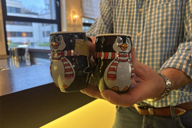 Eine Person hält zwei Pinguin-Tassen vom Weihnachtsmarkt Dortmund 2024.