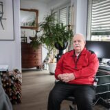 Jürgen (83) sitzt auf einem Bürostuhl an seinem Schreibtisch im Apartment.