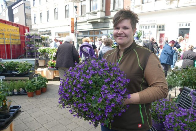 Blumenhändlerin Melanie Jentsch hält beim Blumen- und Kreativmarkt in Herten einen lilafarbenen Strauß aus Blumen in der Hand.
