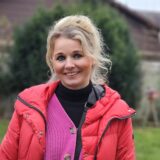 Isabel Auffenberg steht offenbar auf einer Rasenfläche. Sie trägt eine rote Jacke und lächelt in die Kamera.