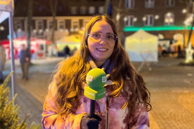 Redakteurin Lara Teschers steht mit einem Mikrofon in der Hand auf dem Dattelner Tigg.