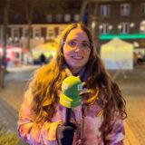 Redakteurin Lara Teschers steht mit einem Mikrofon in der Hand auf dem Dattelner Tigg.