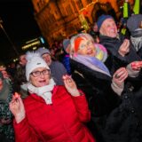 Menschen in Winterkleidung stehen am 13. Dezember 2024 auf dem Rathausplatz Recklinghausen und halten für einen Weltrekord-Versuch LEDs in den Händen.
