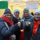 Vier Frauen stehen nebeneinander lächeln in die Kamera und stoßen mit Eierlikörpinnchen an.