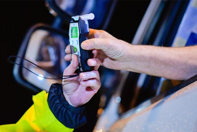 Ein Polizist reicht einem Lastwagenfahrer ein Alkoholmessgerät in die Fahrerkabine.