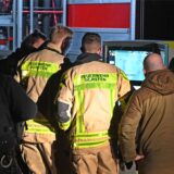 Einsatzkräfte von Polizei und Feuerwehr schauen sich die Aufnahmen einer Drohne auf einem Bildschirm an.