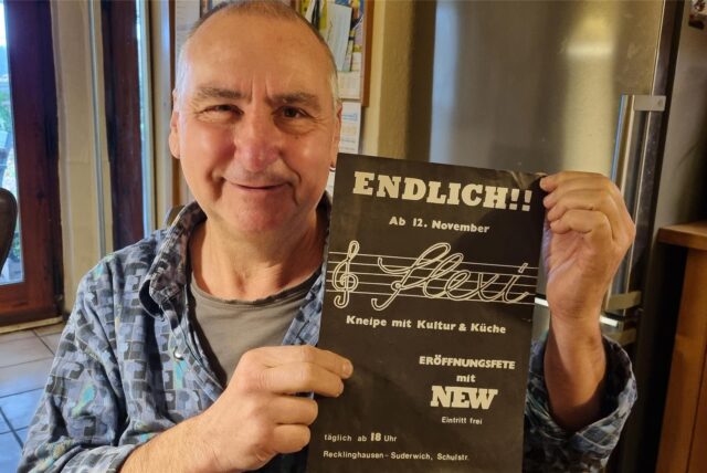 Flexi-Mitbetreiber Gregor Keller hält das Plakat zur Eröffnung der Recklinghäuser Kult-Konzert-Kneipe aus dem Jahr 1982 in die Kamera.