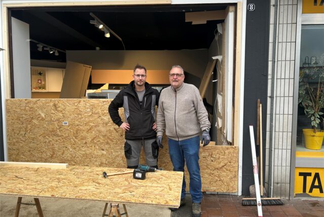 Zwei Männer stehen vor Spanplatten, die das Loch in der Wand des Küchenstudios Brauckhoff in Datteln schließen sollen.