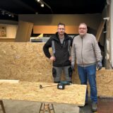 Zwei Männer stehen vor Spanplatten, die das Loch in der Wand des Küchenstudios Brauckhoff in Datteln schließen sollen.