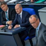 Bundeskanzler Olaf Scholz (SPD) sitzt neben Robert Habeck und schaut misstrauisch zu Friedrich Merz.