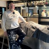 Ein Mann in Arbeiterhose sitzt in einer Bar in Waltrop auf einer Leiter. Seine Hand stützt er auf den Tresen