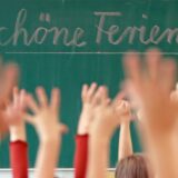 Schüler strecken ihre Arme in die Luft und freuen sich auf Ferien.